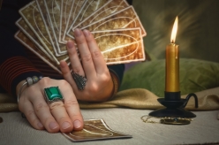 Tarot cards and fortune teller desk table. Future reading. Woman fortune teller holding in one hand a deck of tarot cards and shows a one card by another hand.