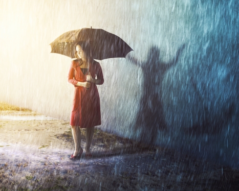 A woman caught in a rain storm with a different shadow